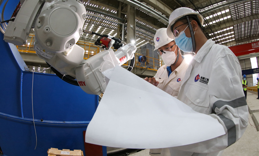 在后續(xù)工序中，為了充分利用好現(xiàn)有資源，項(xiàng)目組開始著手提高項(xiàng)目一體化率。依據(jù)涂裝車間的空間容積，項(xiàng)目團(tuán)隊(duì)在生活樓建造中創(chuàng)新采用“六層三段”一體化建造方法，從而大大減輕了油漆破損和高空作業(yè)的風(fēng)險(xiǎn)，總裝工效大幅提升。圖為現(xiàn)場工程師對智能焊接機(jī)器人進(jìn)行調(diào)試工作。