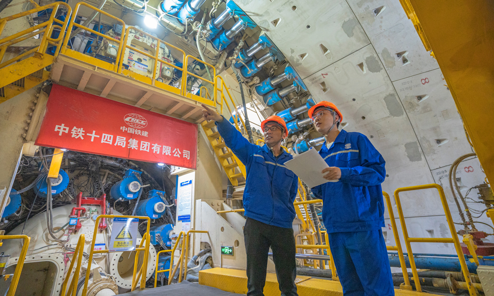 針對工程特點和項目需求，中鐵十四局對盾構機進行了針對性設計優化，聯合研發了具有自主知識產權的“新穿越號”盾構機，配置高承壓主驅動密封、大流量泥水沖刷環流系統、高效物料運輸及智能化預制構件同步拼裝技術、壁后同步注漿密實度檢測系統等多項關鍵技術，大幅度提高盾構機的適應性和可靠性，為工程順利實施保駕護航。圖為技術人員正在檢查“新穿越號”盾構機的掘進狀態。