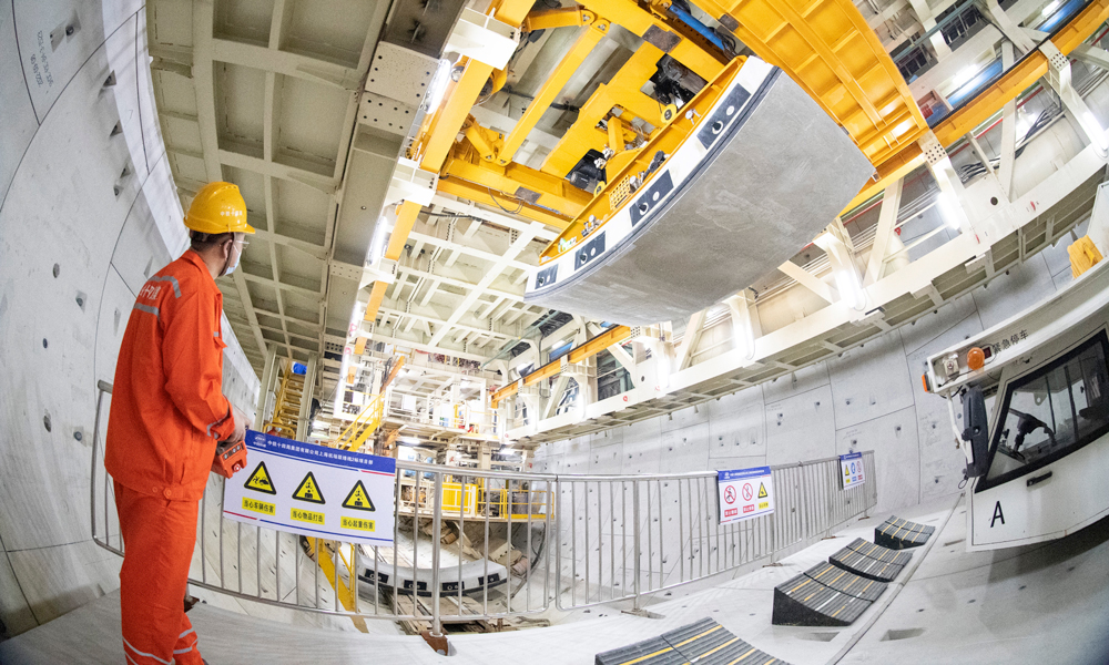 據介紹，上海機場聯絡線在國內首次采用全預制裝配結構體系，開創了類似施工工藝先河。面對預制構件體量大、單構件尺寸大、安裝節點精度要求高、拼裝難度大等要求，項目團隊成立工匠工作室，圍繞全預制拼裝開展課題研究，在國內首次研發弧形件精調裝置，將拼裝精度控制在1毫米以內；在國內首次研發應用中隔墻拼裝設備，實現中隔墻的自動抓取到精度控制的智能一鍵式拼裝，單月最高拼裝達到1200米，創造了全線最快拼裝記錄。圖為施工人員正在進行隧道管片吊裝。