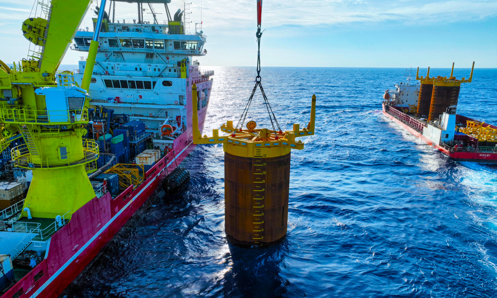 項目部根據吸力樁重心位置量身定制3套吊裝索具，確保起吊時樁體垂直于海平面。現場強化定位精度控制，布控6個定位信標，形成“六邊形”定位陣校準方陣。投入兩臺ROV（水下機器人），采用“阻尼艏向調整法”進行艏向細微調整，保證艏向精度。貫入作業中，船舶吊機和ROV協同作業，精準控制鉤頭載荷和貫入壓力，確保吸力樁緩慢平穩沉降。最終實現了3套吸力樁一次性高精度貫入成功。圖為吸力樁安裝作業現場。