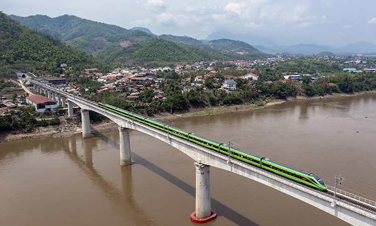 今年恰逢共建“一帶一路”倡議提出十周年。十年來，“一帶一路”倡議合作碩果累累，陸續(xù)建成的一系列標(biāo)志性項(xiàng)目助力各國發(fā)展，為各國人民帶來實(shí)實(shí)在在的好處。從空中俯瞰，這些“國家地標(biāo)”盡顯恢弘大氣，成為“中國建造”的閃亮名片。中老鐵路北起中國昆明，南抵老撾萬象，全長1035公里，是“一帶一路”共商合作、共建項(xiàng)目、共享紅利的生動(dòng)例證。截至10月3日，中老鐵路開通運(yùn)營滿22個(gè)月，累計(jì)運(yùn)輸貨物2680多萬噸，其中進(jìn)出境貨運(yùn)量550萬噸，貨物品類增加至2700多種。圖為2023年5月28日，中老鐵路客運(yùn)列車通過老撾瑯勃拉邦湄公河特大橋。新華社發(fā)（陳暢?攝）