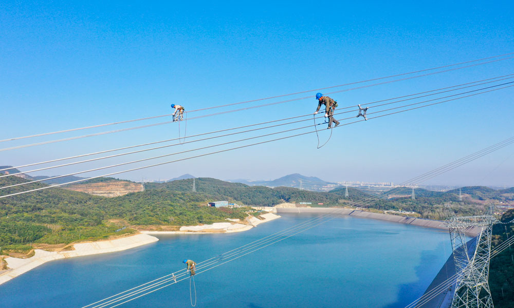 國家電網江蘇省送變電有限公司輸電人員在高空走線驗收消缺。