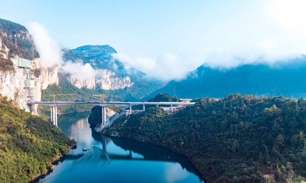 渝湘復線高速公路總里程280公里，由巴南至彭水、彭水至酉陽、武隆至道真3條路組成，平均橋隧比80%。圖為阿蓬江大橋施工現場航拍側景。