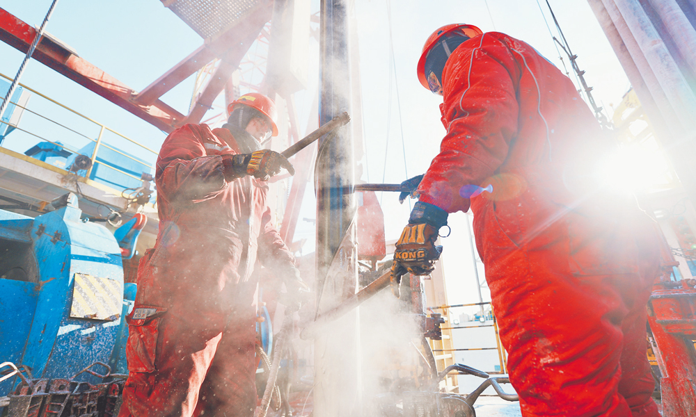 “海洋石油924”鉆井平臺上，鉆工不畏風寒，配合使用刮泥器清潔鉆具泥漿。 金鑫鑫 攝