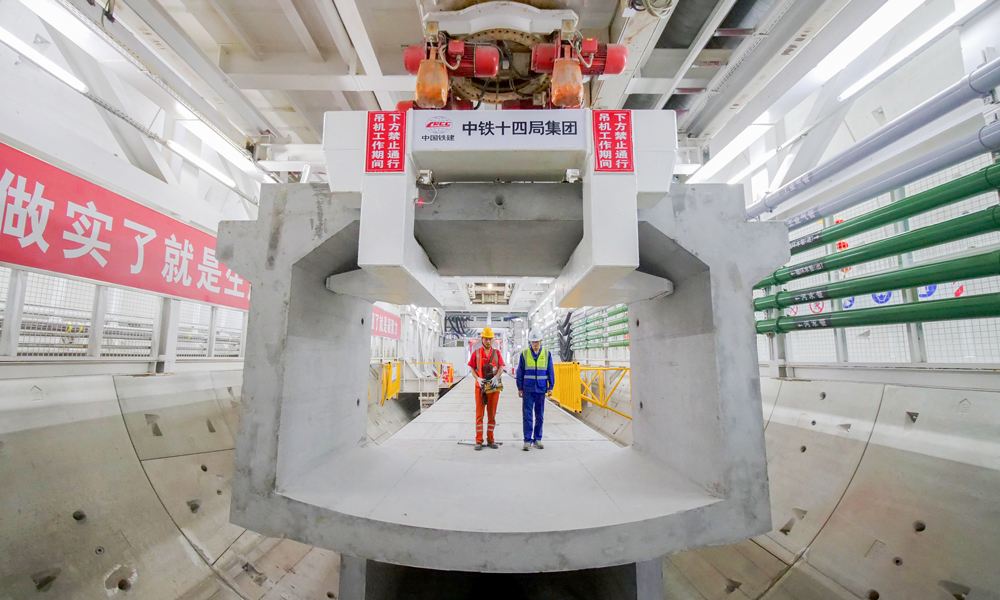 日前，中國鐵建重點項目搶抓施工黃金期，迅速掀起大干熱潮。圖為3月13日，在重慶市南岸區南山下140多米深處，中鐵十四局承建的重黔鐵路長江隧道建設者在隧道內拼裝箱涵。