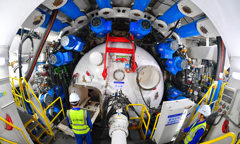 通甬高鐵是我國“八縱八橫”高鐵網沿海通道的重要組成部分，建成后，將與京滬高鐵、滬寧沿江高鐵、滬昆高鐵、寧波至臺州至溫州高鐵等多條線路相連，進一步完善長三角地區路網結構布局，對于推進長三角高質量一體化發展具有十分重要的意義。圖為建設者在盾構機內巡查。