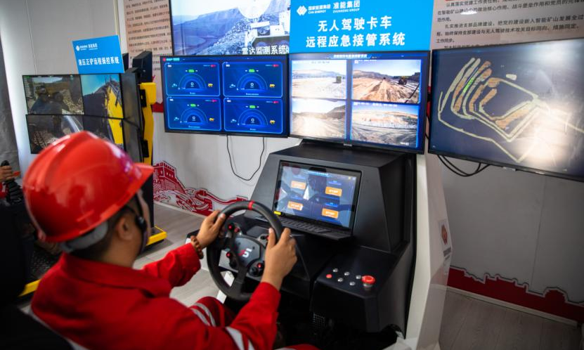 在準(zhǔn)能集團黑岱溝露天煤礦智能礦山建設(shè)現(xiàn)場指揮中心，技術(shù)員正在通過無人駕駛卡車遠(yuǎn)程應(yīng)急接管系統(tǒng)實時監(jiān)控行車路線。該設(shè)備用于對無人駕駛卡車監(jiān)控和遠(yuǎn)程應(yīng)急接管，可有效保障無人駕駛運輸系統(tǒng)的持續(xù)作業(yè)，為無人駕駛安全提供保障。該礦運用多編組車輛智能化調(diào)度與管理系統(tǒng)，實現(xiàn)三編組無人駕駛卡車同時運行和多車智能協(xié)同裝卸，大幅提升了無人作業(yè)效率。包文學(xué) 攝