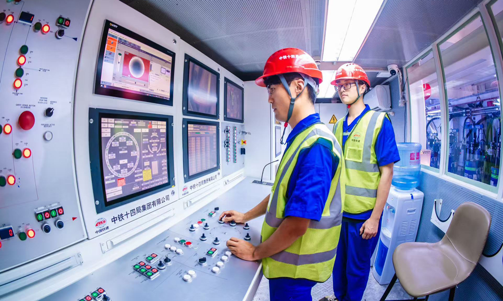 針對施工重難點，中鐵十四局結(jié)合深耕黃河流域盾構(gòu)施工經(jīng)驗，量身打造“山河號”盾構(gòu)機(jī)，配備了配備帶壓復(fù)合型刀盤、伸縮式主驅(qū)動等先進(jìn)技術(shù)，并搭載了超前地質(zhì)預(yù)報、地層界面識別等智能化裝備系統(tǒng)，盾構(gòu)機(jī)總裝達(dá)到世界先進(jìn)水平。圖為駕駛艙內(nèi)，技術(shù)人員操作盾構(gòu)機(jī)向前掘進(jìn)。