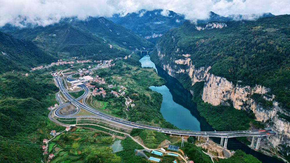 阿蓬江大橋不僅橫跨雄奇秀美的阿蓬江，一端還連接著穿越“90度懸崖峭壁”的龔灘隧道。隧道出口陡崖風化、溶蝕嚴重，施工既存在危巖落石隱患，又容易導致施工污染。為此，建設者創新設計了8級陡崖加固方案，不僅克服了坡腳地質不穩、受力復雜等難題，還顯著降低了廢棄物對烏江可能造成的污染，有力守護了區域的綠水青山。圖為渝湘復線高速阿蓬江大橋。