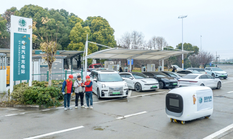 國(guó)家電網(wǎng)安徽馬鞍山供電公司工作人員在高速公路充電站指導(dǎo)客戶操作充電機(jī)器人。