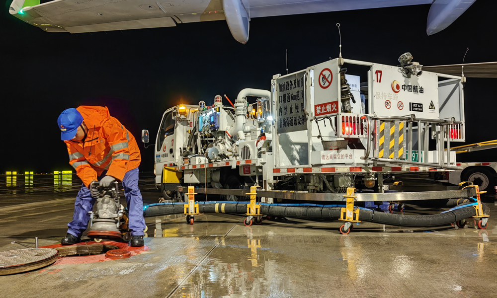 中國航油貴州分公司航空加油站飛機加油員進行雨中加油作業。