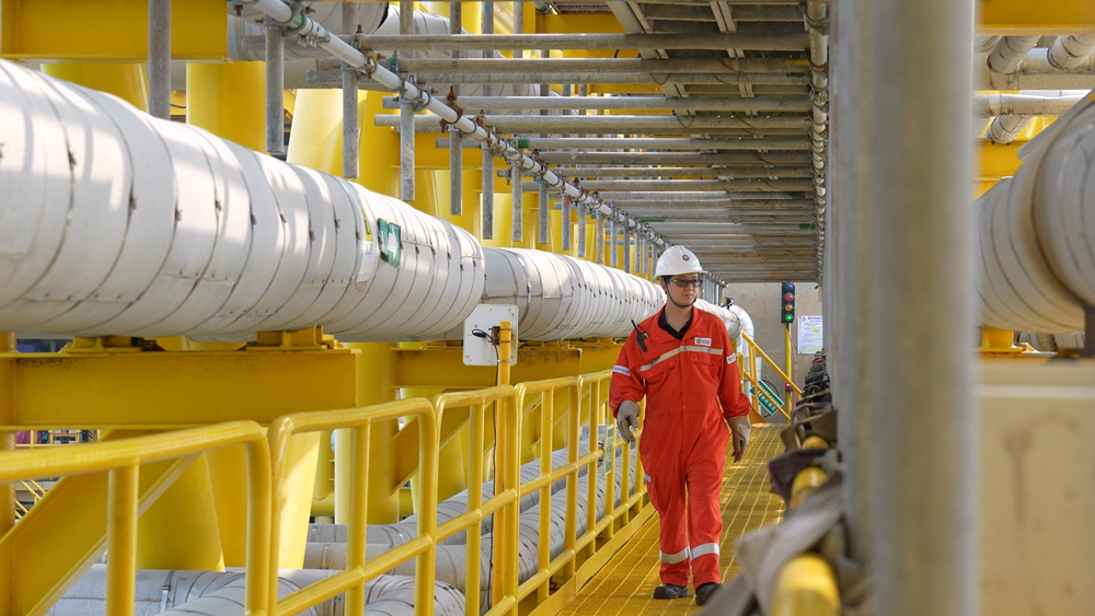 海上生產人員穿過平臺間棧橋進行設備巡檢。