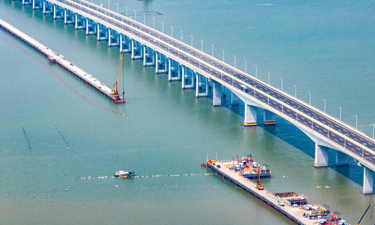 近日，中鐵四局新建漳汕高鐵漳江灣跨海特大橋主棧橋施工現(xiàn)場機械林立，近百名施工人員全力沖刺棧橋合龍節(jié)點目標。漳汕高鐵線路全長約175公里，全線涉及3座跨海大橋，其中漳江灣跨海特大橋為全線控制性工程，橋梁全長5.8公里，海域部分橋梁長5公里。為解決海上材料、設(shè)備運輸和人員通行和主體工程作業(yè)要求，四局建設(shè)者在漳江灣海域搭設(shè)長4.7公里、寬8米的主棧橋。目前，大橋樁基、承臺、墩身施工正在有序推進建設(shè)。