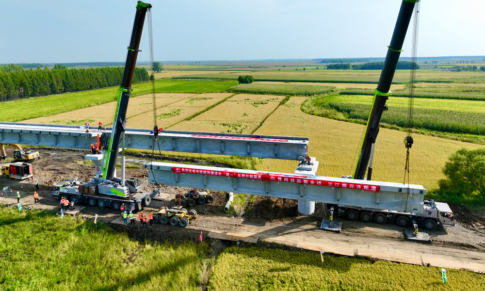 此次進入架梁階段的佳木同江特大橋位于同江至同江北改建段，是全線控制性工程，橋梁全長10435.14米，采用單線T梁結(jié)構(gòu)設(shè)計，是我國目前中歐班列三大通道中口岸段最長新建橋梁。圖為架橋機在架設(shè)梁體。