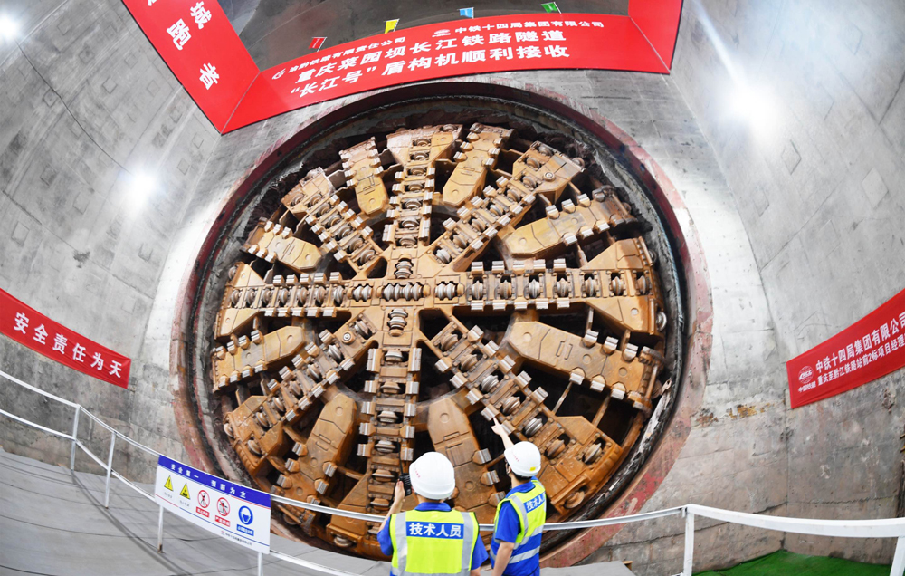 重慶菜園壩長江鐵路隧道是渝廈高鐵全線關鍵控制性工程。隧道位于重慶市渝中區與南岸區，為單洞雙線高速鐵路隧道，全長11942米，起始于重慶火車站，沿途下穿市政道路、高架橋梁、軌道交通線、多處建筑群、長江主航道及南山山體，整體呈現“穿山、穿城、穿江、穿水”的復雜特點，施工難度大、技術要求極高。圖為技術人員檢查刀盤磨損情況。