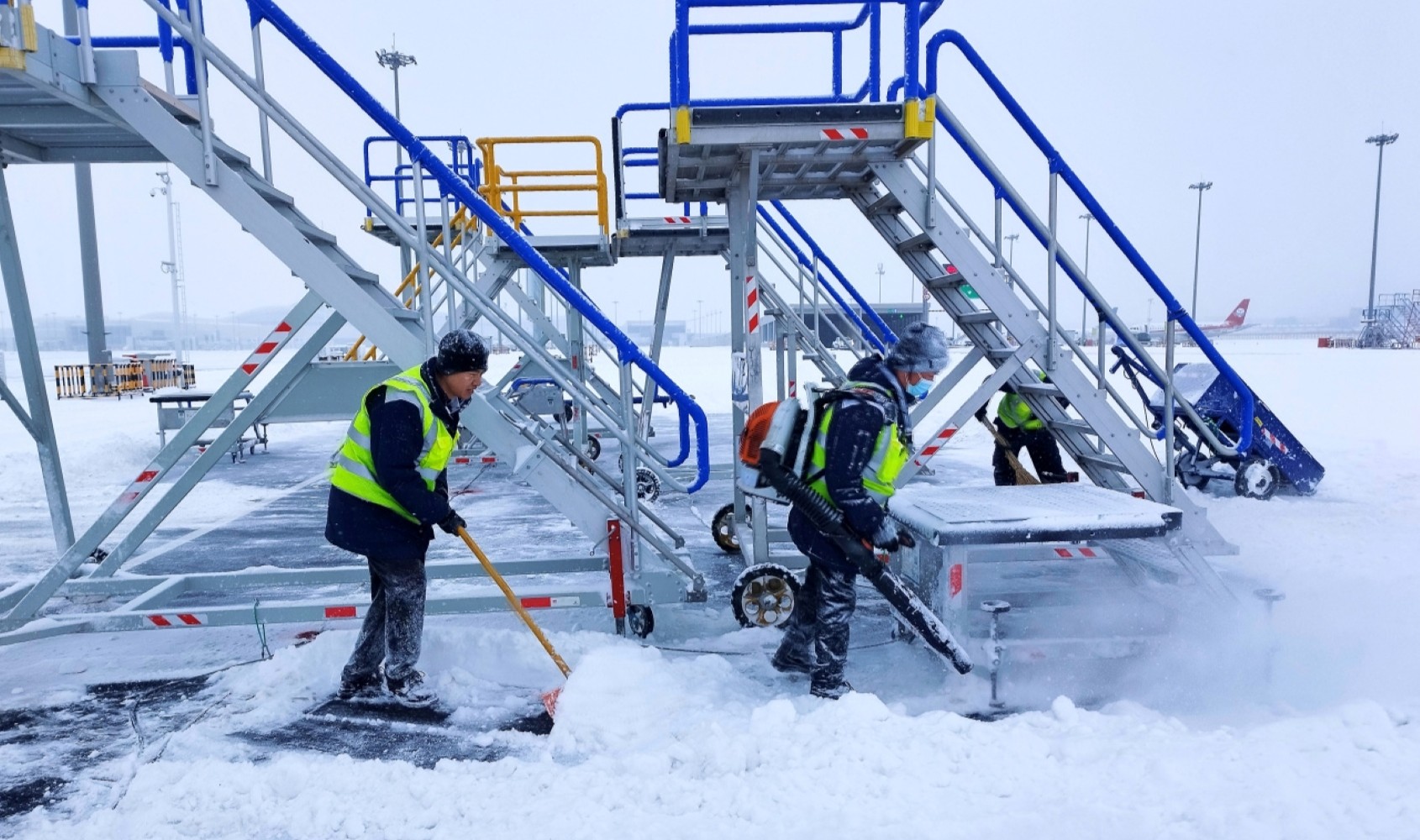 在烏魯木齊天山國際機場，中航集團工作人員清除機坪積雪。