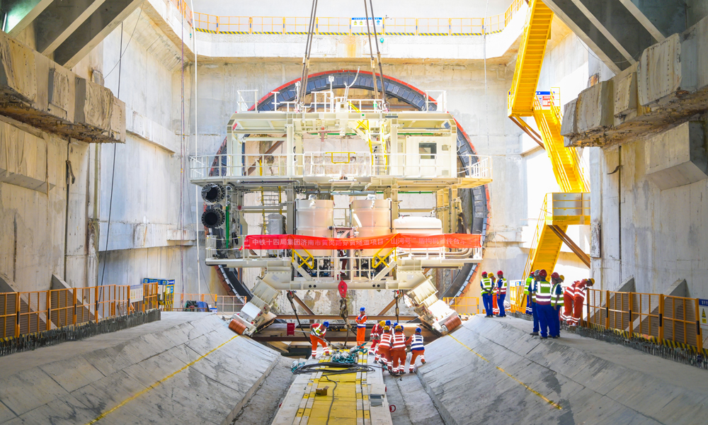 濟南黃崗路穿黃隧道工程是構(gòu)建南北向跨黃河的大通道之一，建成后，將助力濟南主城區(qū)與新舊動能轉(zhuǎn)換起步區(qū)互聯(lián)互通，有力推進起步區(qū)建設(shè)全面提速，促進濟南從“大明湖時代”邁向“黃河時代”，為黃河流域生態(tài)保護和高質(zhì)量發(fā)展提供有力支持。圖為始發(fā)井內(nèi)，盾構(gòu)機臺車吊裝到指定位置。