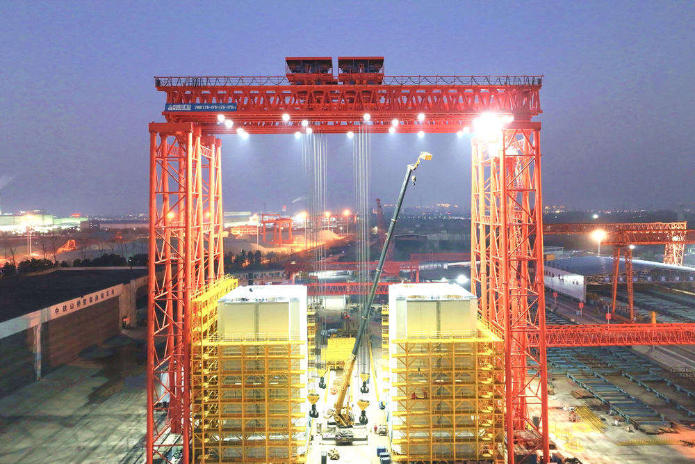 面對大橋鋼塔制造精度、變形控制、自動化焊接率等要求極高情況，中鐵山橋配備了空氣等離子數(shù)控切割機、龍門式智能焊接機器人系統(tǒng)、板單元數(shù)控矯正機床、三維數(shù)字掃描等裝備，全面提升主塔制造自動化水平和焊接質(zhì)量；開展技術(shù)工藝創(chuàng)新，通過改進拼裝工藝、優(yōu)化焊接順序、設(shè)計專用工裝等手段，確保了主塔毫米級精度制造。圖為張靖皋長江大橋主塔立式預(yù)拼裝現(xiàn)場。