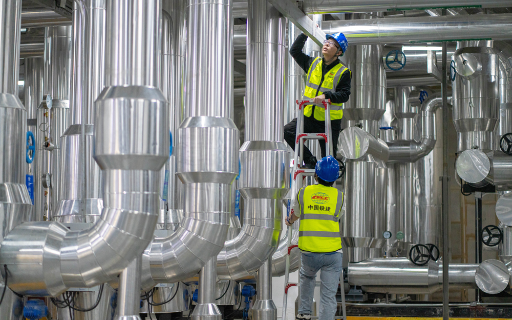 通過博鰲近零碳示范區運行管理中心，可以實現整個零碳示范區碳監測、碳核算及智慧化運維。中心搭載了智慧能源管控平臺，該平臺運用“CIM+BIM”建設3D數字孿生東嶼島模型，接入樓宇管控、燈光照明、環境監測等系統，可視化監測管控，定期反饋設備運行狀態，根據建筑空間人數及室外光照強度，動態調節空調及燈光。圖為中鐵建設運維工程師檢查制冷機房設備運行狀態。