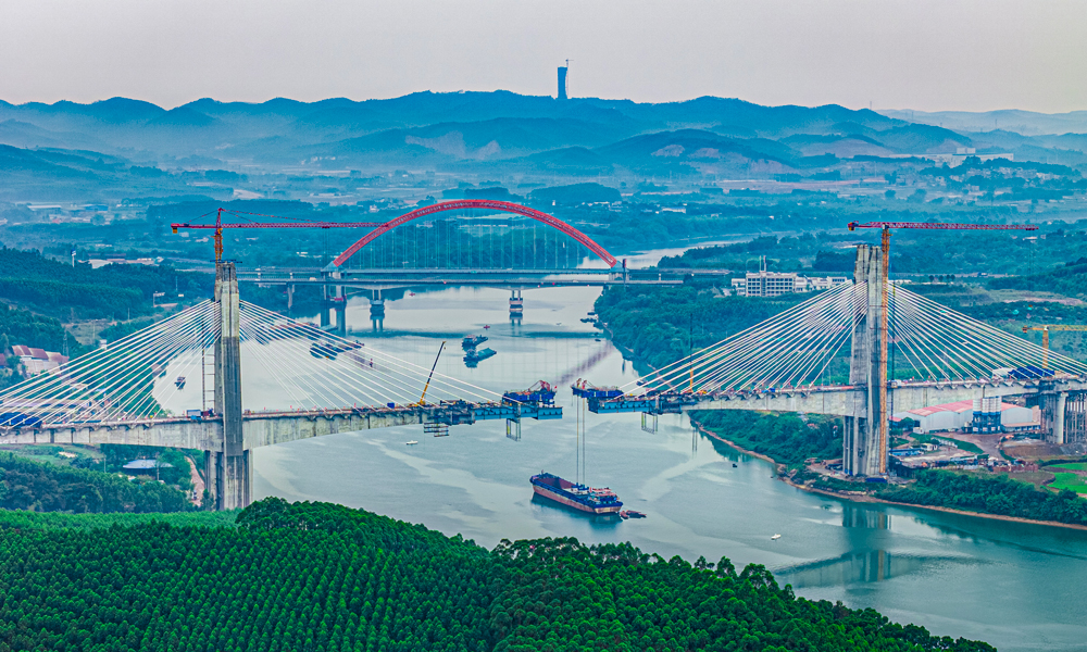 六律邕江特大橋跨越邕江東西兩岸，采用墩塔固結(jié)、墩梁豎向支撐的半漂浮結(jié)構(gòu)體系。主橋全長622米，橋梁主跨長320米。開工建設(shè)以來，建設(shè)團隊持續(xù)優(yōu)化施工方案、強化現(xiàn)場管控，嚴(yán)格執(zhí)行各項施工規(guī)范及操作規(guī)程，克服了地質(zhì)熔巖發(fā)育、超深流沙層、超大溶洞、高塔施工難度大、懸臂澆筑長等難題，圓滿完成大橋建設(shè)任務(wù)。