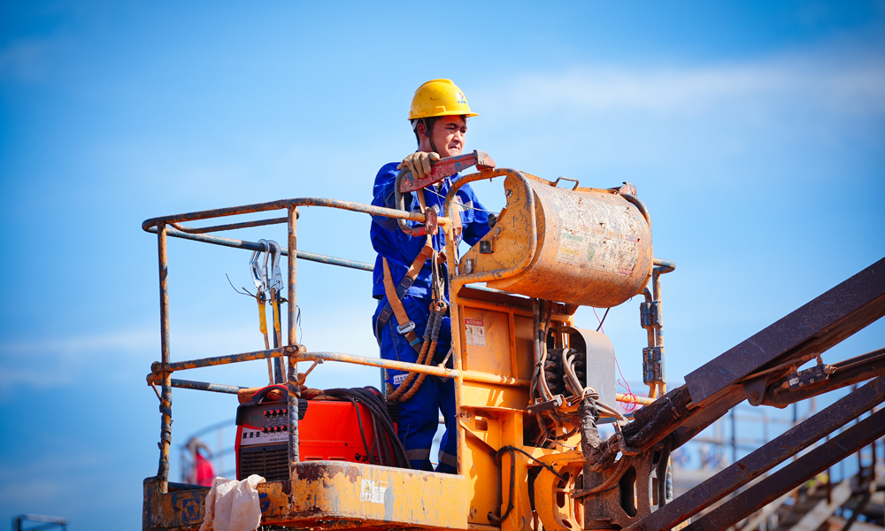 在陸地，建設(shè)人員倒排工期快施工，實現(xiàn)了原油處理站、生產(chǎn)水處理站、天然氣液化站、石油氣液化站、變電站、5G基站“六站合一”。其中，生產(chǎn)水處理站采用四級工藝處理生產(chǎn)水，處理后純凈度高。變電站將綠色岸電變壓后輸至海上平臺，替代傳統(tǒng)的燃氣發(fā)電，減碳效果突出。5G網(wǎng)絡(luò)“連通”海上，為無人機巡檢海上設(shè)施、海面24小時溢油苗頭監(jiān)測等各種智能應(yīng)用鋪筑了“信息傳輸高速路”。圖為施工人員準備登高作業(yè)。