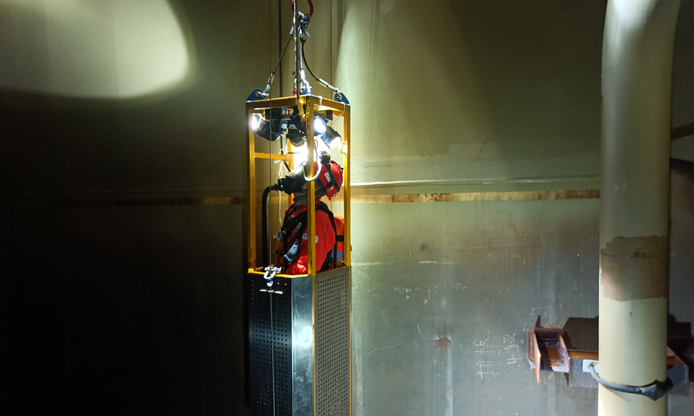 為了確保平臺(tái)凝析油艙處于良好運(yùn)行狀態(tài)，掌握艙內(nèi)設(shè)備運(yùn)轉(zhuǎn)情況，平臺(tái)工作人員會(huì)定期開展清艙檢測(cè)作業(yè)。圖為“深海一號(hào)”現(xiàn)場(chǎng)作業(yè)人員搭乘空間極其狹小的特制工作吊籃進(jìn)入凝析油艙內(nèi)部進(jìn)行檢查。周宇 攝