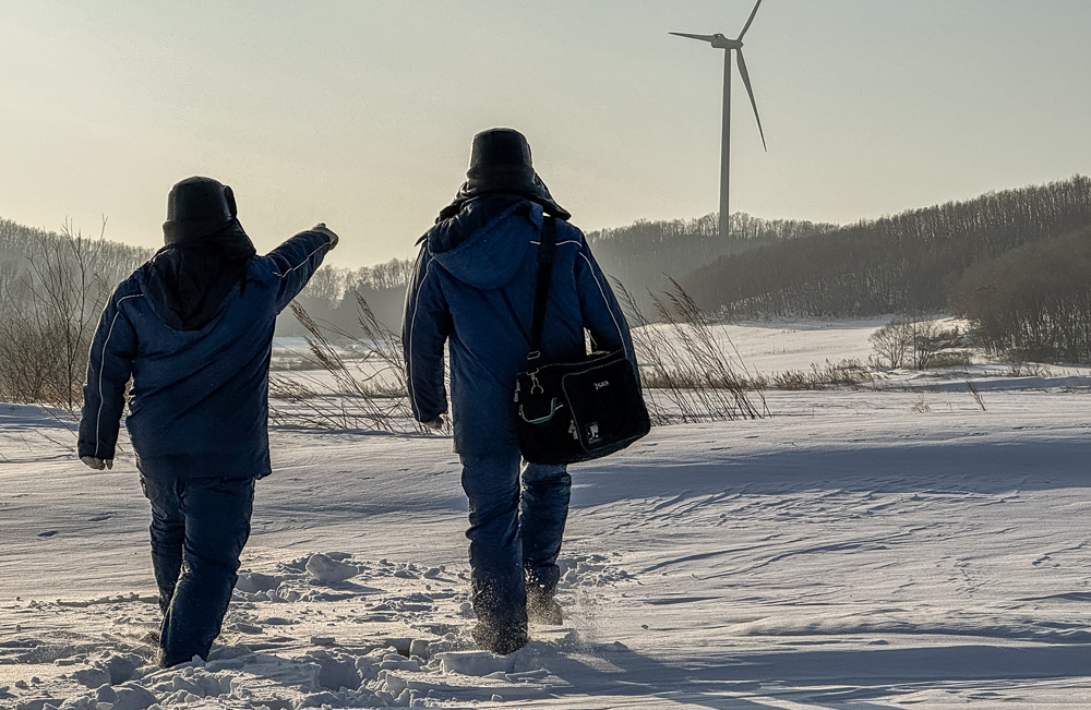 中廣核黑龍江興凱湖風電場接獲天氣預警后，即刻啟動集電線路與風機葉片覆冰應急處置方案，組建“葉片檢查突擊隊”借助無人機檢查葉片覆冰情況，“道路搶修突擊隊”聯合道路維護隊清理檢修道路急彎陡坡積雪，并撒防滑料以保暢通，同時暫停風機檢修防落冰傷人。