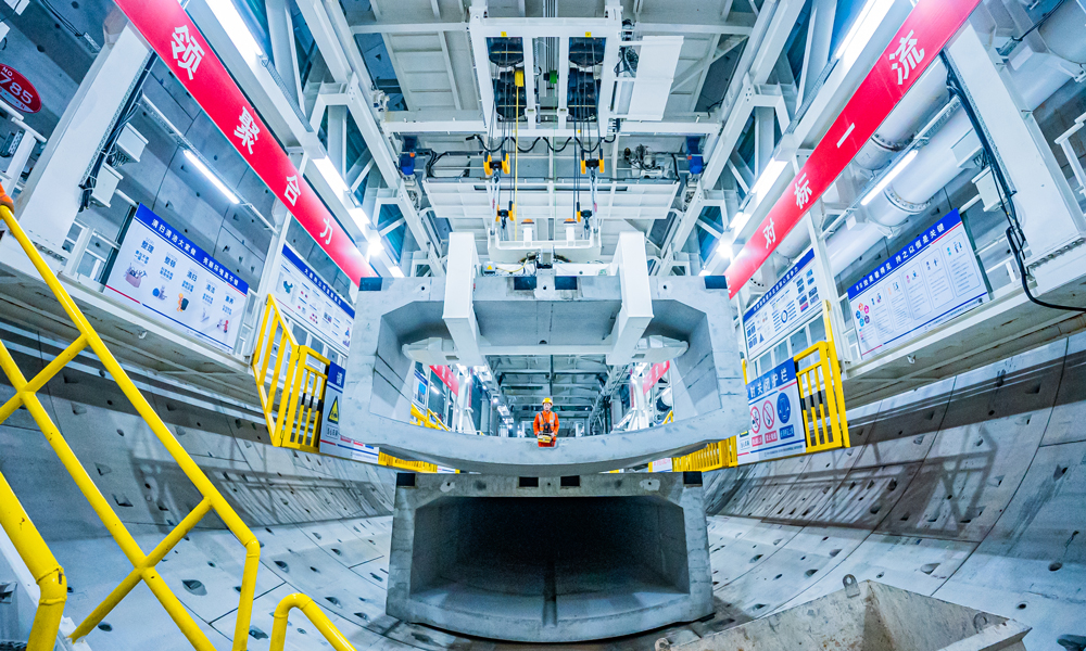 濟南市黃崗路穿黃隧道南起藍翔中路，向北依次下穿二環北路、濟廣高速、南岸大堤、黃河、北岸大堤、鵲山水庫沉沙池，終點與在建G309互通立交相銜接，全長約5755米，其中盾構段長約3290米，盾構機開挖直徑17.5米，為世界最大直徑水下盾構隧道。圖為工作人員正在調運預制管片。