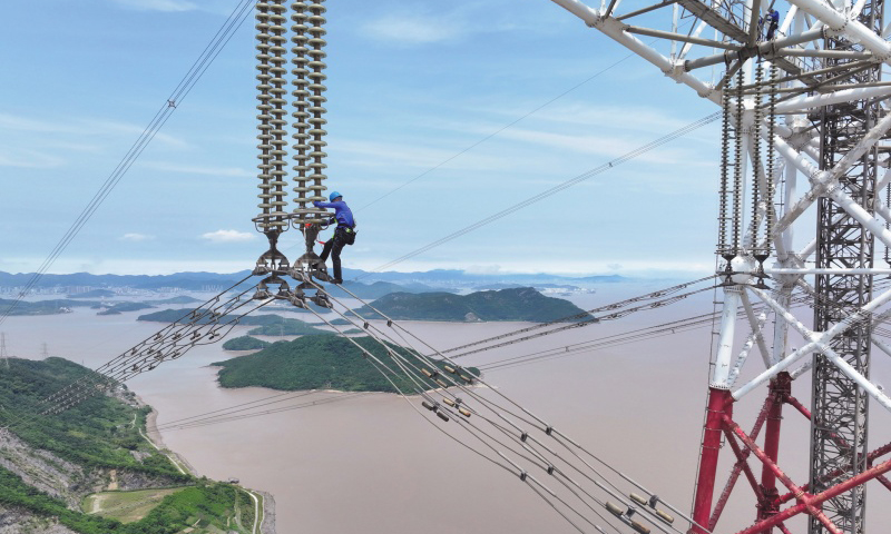 此次檢修規(guī)模大、技術(shù)難度高，洛春5495線、洛曉5496線為跨海輸電線路，連接兩條線路的兩座高370米的輸電鐵塔分別位于舟山大貓山和寧波涼帽山，兩座輸電鐵塔檔距達(dá)2756米。檢修人員登上位于大貓山的輸電鐵塔，在高低落差達(dá)280米、最低點(diǎn)距海面高度超84米的線路開展走線作業(yè)。圖為檢修人員通過絕緣子串下到跨海輸電導(dǎo)線上。