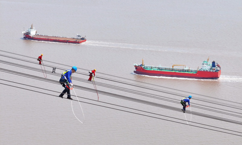 國家電網(wǎng)檢修人員在跨海輸電導(dǎo)線上開展高空走線作業(yè)。