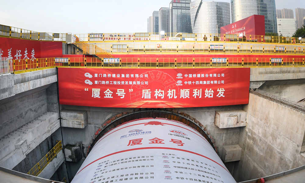 廈金大橋（廈門段）工程起于廈門環(huán)島東路與會展北路交叉口，以隧道形式沿環(huán)島路向北延伸至觀音山，往東以橋梁形式跨越本島東部海域，終點(diǎn)設(shè)互通接入廈門翔安國際機(jī)場，主線長17.34公里。其中，環(huán)島路隧道長3.29公里，采用盾構(gòu)、明挖法施工，盾構(gòu)隧道左右線分別為1.33公里與1.04公里，為雙向六車道，設(shè)計時速80公里，由一臺16米級超大直徑盾構(gòu)機(jī)掘進(jìn)。圖為“廈金號”盾構(gòu)機(jī)始發(fā)現(xiàn)場。