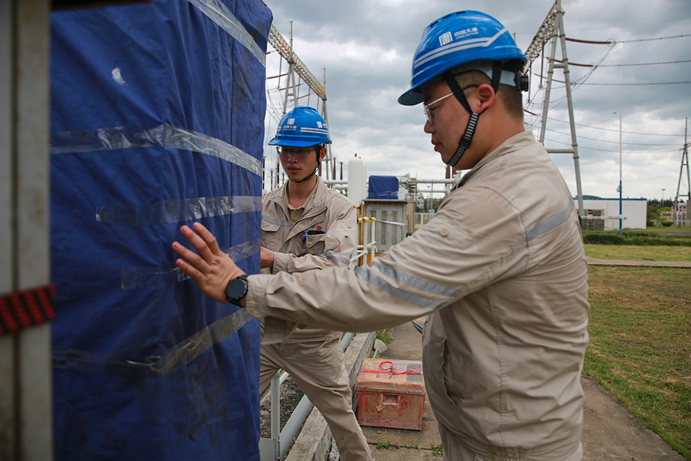 大唐潮州發電公司職工為電氣設備罩設防雨布a.jpg