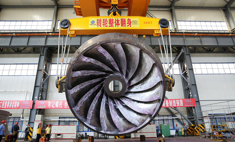 該轉輪是世界首臺百萬千瓦水電機組轉輪，由東方電氣集團東方電機有限公司研發制造。轉輪直徑8.62米、高3.92米，由15塊葉片組成，每個葉片重達11噸，轉輪總重近350噸。而白鶴灘百萬水電機組建成后將達50多米高、8000多噸重，相當于埃菲爾鐵塔的重量。圖為2018年11月18日，白鶴灘水電站首臺轉輪在加工中進行“翻身”。  東方電氣 供圖