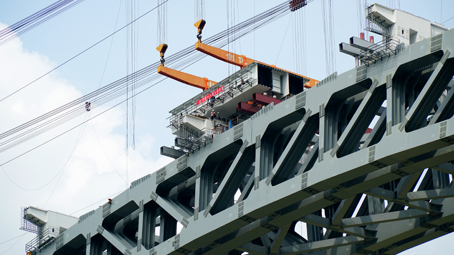 兩側(cè)引橋鋼混結(jié)合梁采用“步履式頂推”新工藝，均由大橋兩端向跨中方向頂推，在兩側(cè)分別搭設(shè)鋼混結(jié)合梁頂推平臺(tái)，并完成鋼混結(jié)合梁的拼裝、焊接、高強(qiáng)螺栓施擰及補(bǔ)涂裝等施工任務(wù)。圖為鋼箱梁節(jié)段落梁。