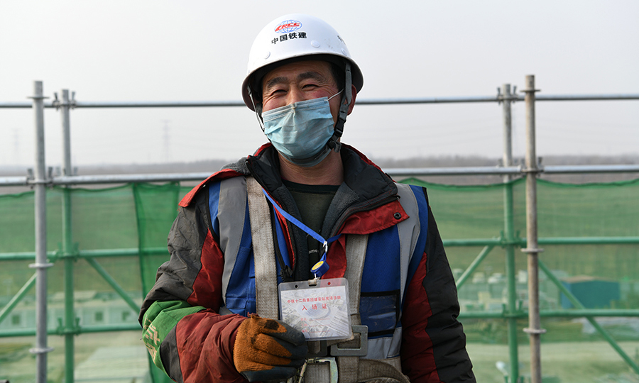 現場每名工人在上崗前都經過地方防疫機構檢測和單位自查，合格后派發通行證，保證安全復工生產。圖為工人展示通行證。（任雙歡 攝）