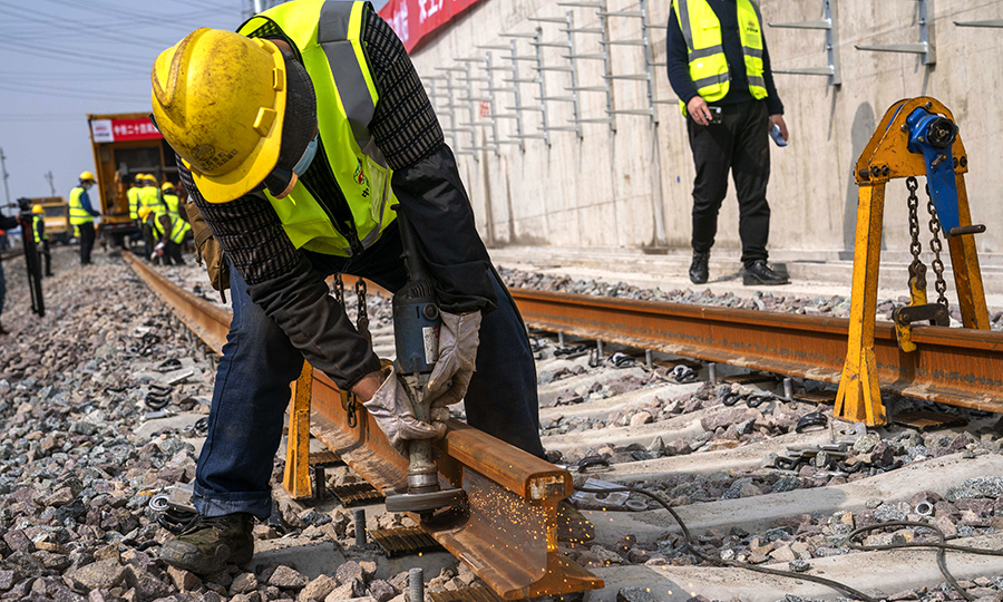 目前，該項目正在進行錦秋路站至顧村公園站區間上下行線無縫線路焊軌、陳太路停車場碎石道床施工。為兌現工期節點目標，項目部正在組織長風公園站基地、姚虹路基地施工人員陸續進場，盡快恢復全標段施工。圖為上海地鐵15號線鋪軌B標工人師傅正在進行除銹作業。