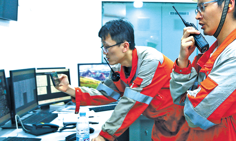 初秋的遼東灣，海面風平浪靜。一艘歸航的拖輪犁開一條長長的水線，船影消逝了，水線卻久久留存。平臺長秦斌無暇遠眺，聽到對講機中“秦臺秦臺，請給中控回電”的呼叫聲，趕忙從飛行甲板快步趕往中控室。圖為平臺長和中控緊盯現場數據。