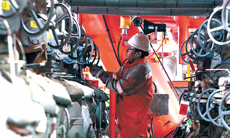 秦斌所在的中國海油旅大21-2油田包括通過冷采開發的A平臺和通過熱采開發的B平臺，自海上“安家落戶”后，兩個平臺便合二為一。整個平臺面積不大，分量卻不輕，B平臺作為我國首個規?；療岵杉夹g集成示范平臺，肩負著單項熱采技術優化、系統熱采技術集成創新應用、熱采新技術試驗等示范性任務，對于渤海油田上產4000萬噸，保障國家能源安全都具有重要意義。圖為井口崗員工正在操作油井管匯閥門，準備對油井進行計量。