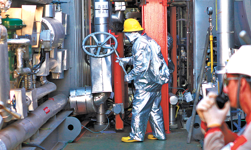 要通過熱采進行稠油開發，平臺生產區密布著蒸汽吞吐作業涉及的247臺設備，設備數量、規模、維保檢修的工作量絲毫不亞于一個中心平臺，生產現場管線密布錯綜，穿梭其中如置身鋼鐵叢林。開始注熱前的調試準備工作，讓秦斌和同事們忙得腳打后腦勺。最多的一天，秦斌一早簽了28份工單，在高峰作業期間，支持船和平臺作業人員有500余人。圖為身著防高溫防護服的操作員正在進行注熱開閥作業。