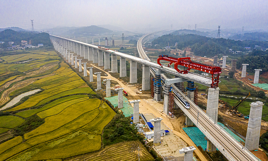 為保證施工順利進行，該項目部經過方案比選，采用了“門式墩鋼蓋梁+簡支箱梁”的形式跨越，大大降低了安全風險，有效縮短了施工周期，并降低了施工成本。圖為10月13日，一列動車從架梁施工現場通過。（彭特 攝）