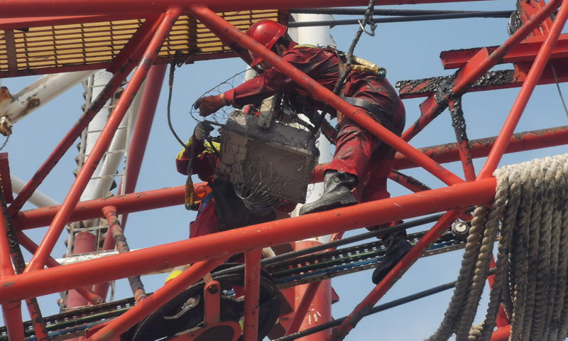 圖為在第19號臺風“天鵝”來臨前，“COSLCRAFT”鉆井平臺電氣師正在對吊車扒桿照明燈進行加固。