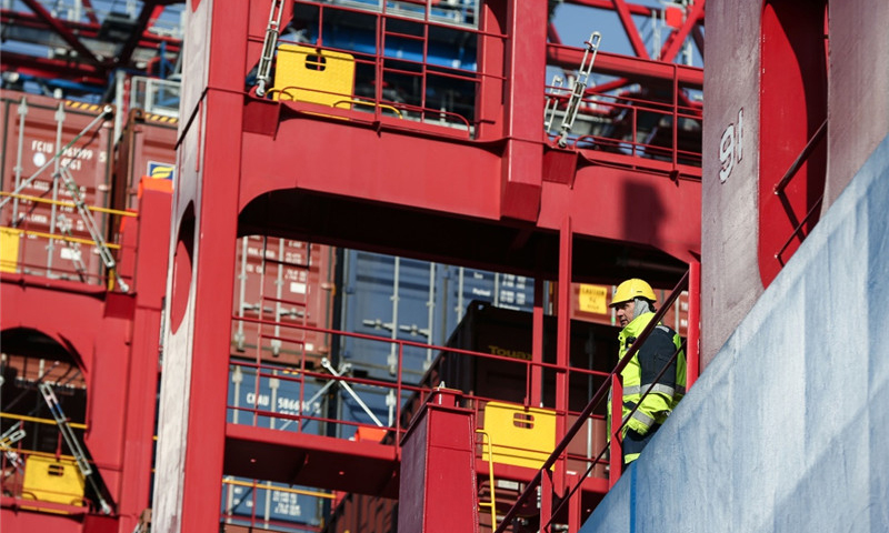 2月23日，在德國(guó)漢堡港，一名工作人員在集裝箱船“中遠(yuǎn)海運(yùn)白羊座”號(hào)上參與集裝箱卸載工作。（新華社記者 單宇琦 攝）