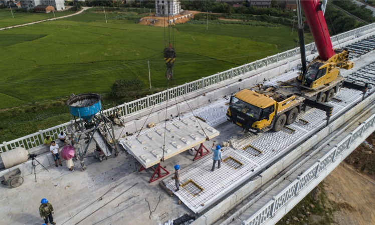 昌贛高鐵是京九高鐵的重要組成部分，總長(zhǎng)約415.2公里，設(shè)計(jì)行車速度為350公里/小時(shí)。圖為8月30日，中鐵十一局職工在江西省豐城市境內(nèi)的昌贛高鐵孫渡特大橋上吊裝無砟軌道板。（新華社記者 杜華舉 攝）